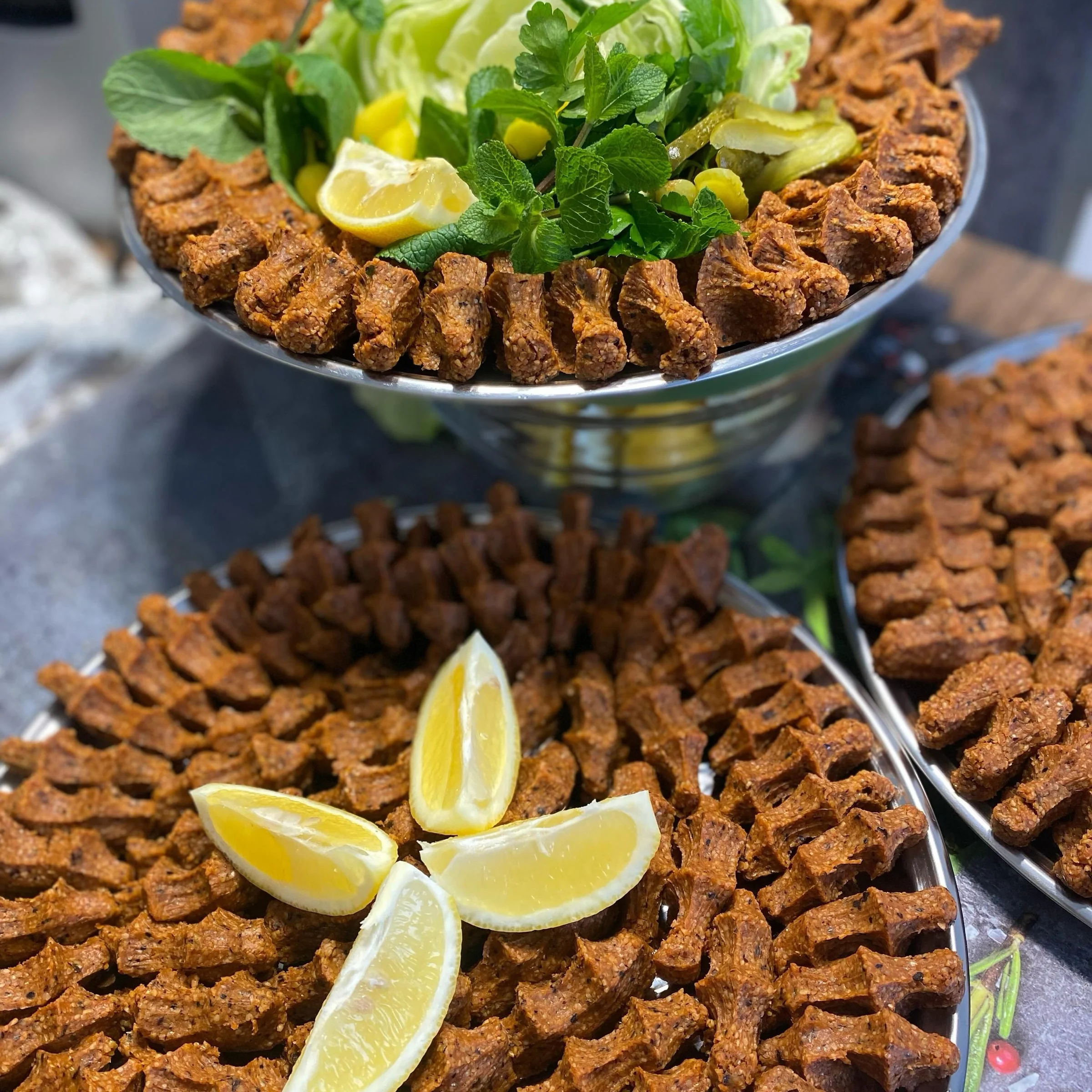 Frisch handgekneteter Çiğköfte mit Zitronen auf silberner Schale