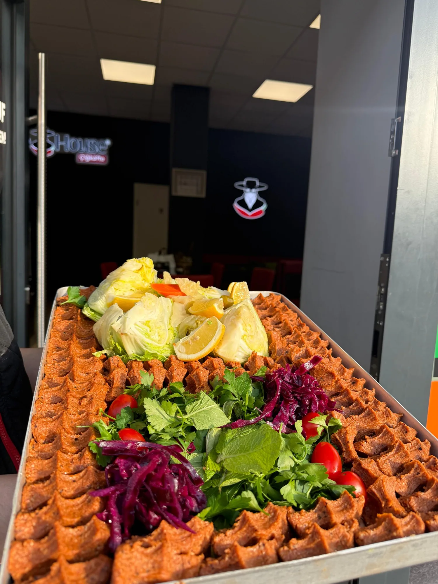 Frisches Çiğköfte-Tepsi vor der Chee House Logo-Wand